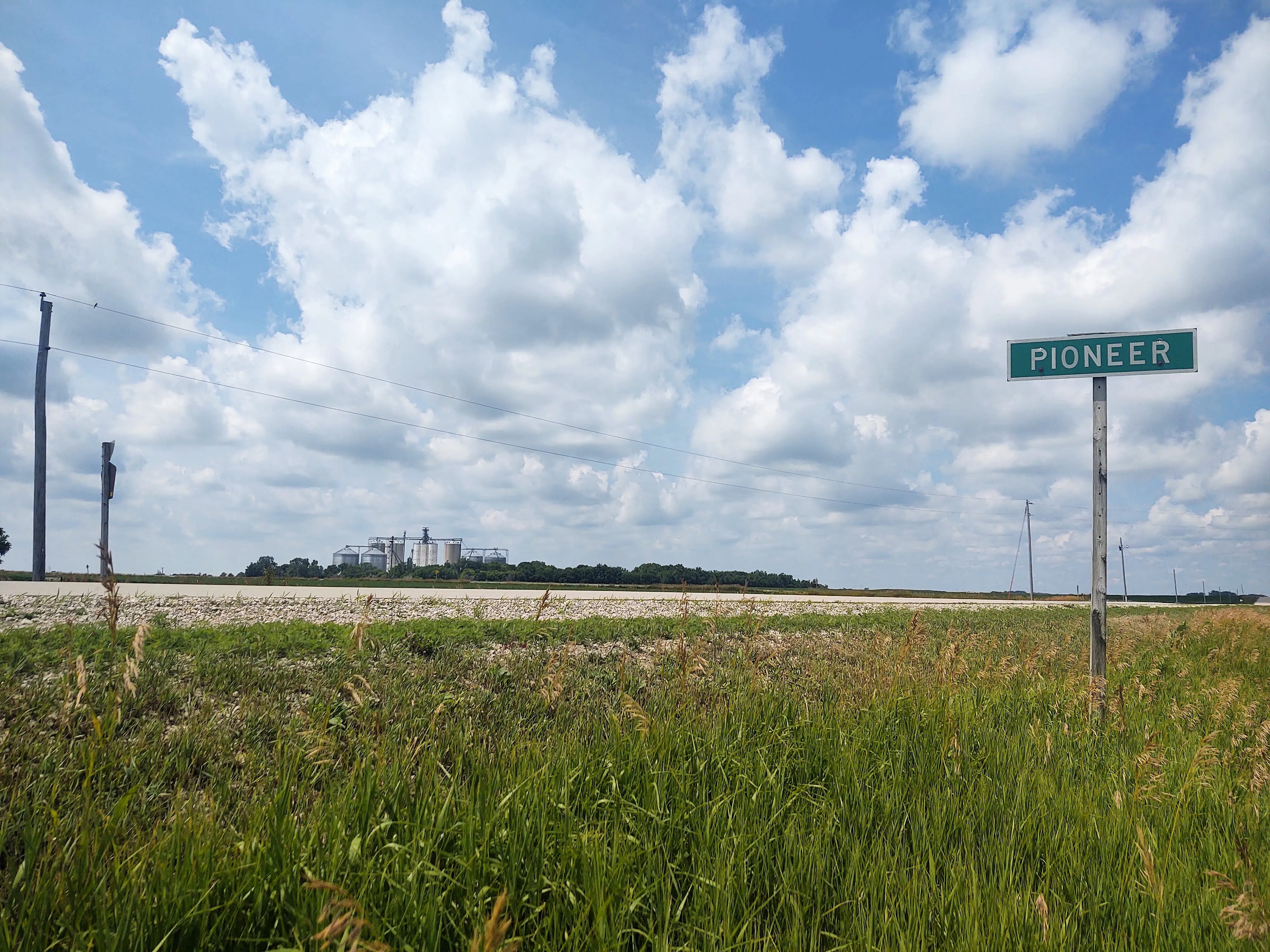 Photograph of a rural highway. A sign in the foreground simply says PIONEER.